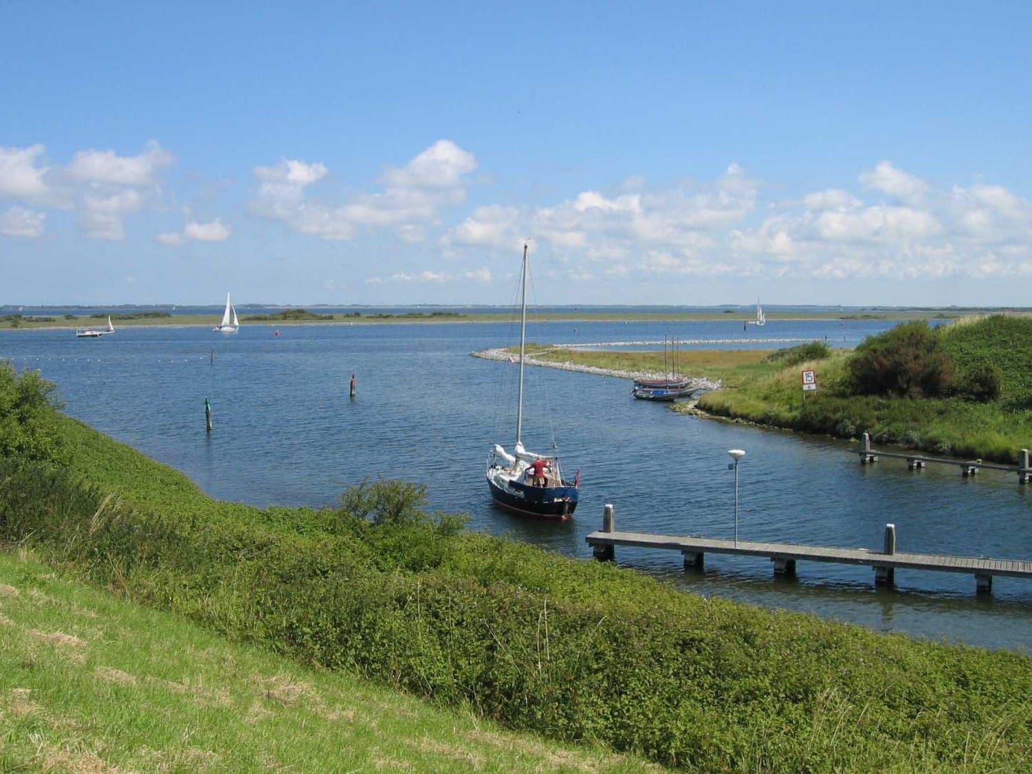 grevelingenmeer-brouwershaven Zeilboot vaart de haven binnen op het Grevelingenmeer onder een strakblauwe zomerhemel